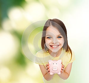 Beautiful little girl with piggy bank