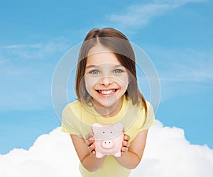 Beautiful little girl with piggy bank