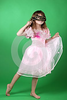 Beautiful little girl in pink butterfly dress and carnival mask dancing