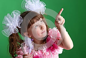 Beautiful little girl in a pink dress and with a glass in which a butterfly, points her finger up