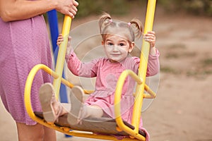 Beautiful little girl in pink on a swing.