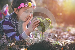 Beautiful little girl planting a heart-shaped tree and dreaming of a beautiful future