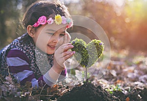 Beautiful little girl planting a heart-shaped tree and dreaming of a beautiful future