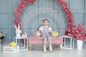 Beautiful little girl playing with colorful Easter eggs and Easter bunny. Easter interior room. Family holidays, traditions. Harve