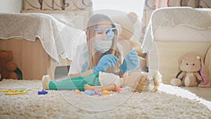 Beautiful little girl playing doctors with doll at home.