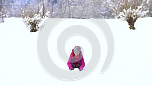 Beautiful little girl is playing in the field in the snow. Have fun throwing snow up.