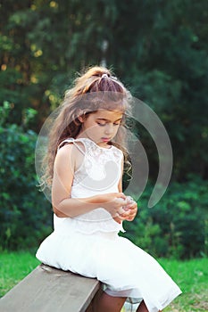 Beautiful little girl  playing with flowers in sunny spring park. Happy cute child having fun outdoors at sunset