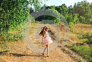 Beautiful little girl  playing with flowers in sunny spring park. Happy cute kid having fun outdoors at sunset