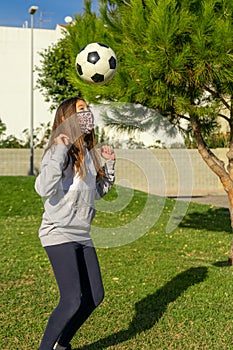 Beautiful little girl playing soccer in a nice park with natural grass on a sunny winter day. Copy space