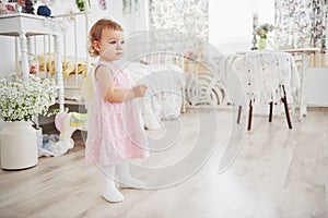 Beautiful little girl playing toys. Blue-eyed blonde. White chair. Children`s room. Happy small girl portrait. Childhood