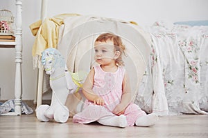 Beautiful little girl playing toys. Blue-eyed blonde. White chair. Children`s room. Happy small girl portrait. Childhood