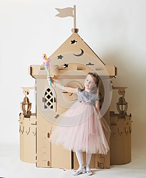 Beautiful little girl in princess dress playing with her toy castle.