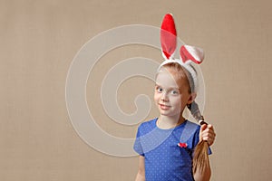 Beautiful little girl with rabbit ears holds her hair