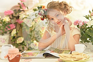 Beautiful little girl reading magazine