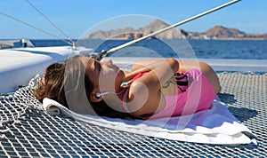 Beautiful little girl relaxing in sailboat while listening to music on the ocean