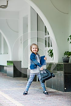 A beautiful little girl, a schoolgirl, in the afternoon near the school, in a school uniform