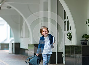 A beautiful little girl, a schoolgirl, in the afternoon near the school, in a school uniform