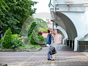 A beautiful little girl, a schoolgirl, in the afternoon near the school, in a school uniform