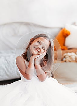 Beautiful little girl sits on the floor in a light room. Happy Smiling Child