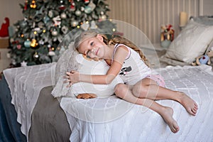 Beautiful little girl sitting near the Christmas tree.