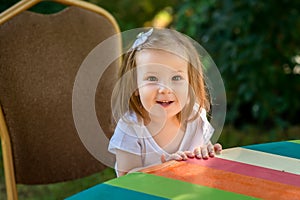 Beautiful little girl sitting on a wooden bench and have a cookie.