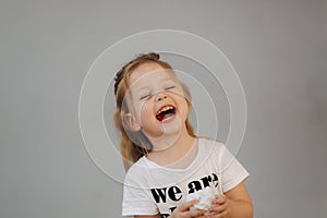 Beautiful little girl smile to camera. Gray background. we are all kids