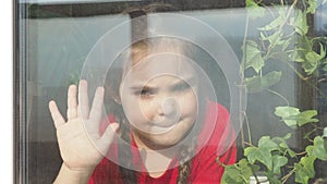 Beautiful little girl smiling and watching out the window. A child looks out the window. Portrait of cheerful kid. self