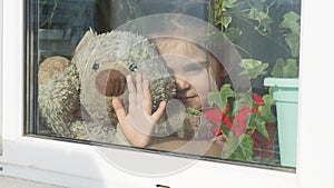 Beautiful little girl smiling and watching out the window. A child looks out the window. Portrait of cheerful kid. self