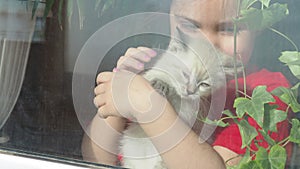 Beautiful little girl smiling and watching out the window. A child looks out the window. Portrait of cheerful kid. self