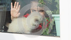 Beautiful little girl smiling and watching out the window. A child looks out the window. Portrait of cheerful kid. self