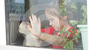 Beautiful little girl smiling and watching out the window. A child looks out the window. Portrait of cheerful kid. self