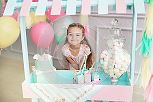 Beautiful little girl stands behind the toy candy shop