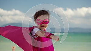 Beautiful Little Girl in the Superhero Costume, Dressed in a Pink Cloak and the Mask of the Hero. Plays on the