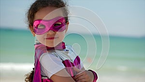 Beautiful Little Girl in the Superhero Costume, Dressed in a Pink Cloak and the Mask of the Hero. Plays on the