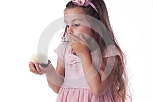 Beautiful little girl surprised from a tasty big chocolate coconut candy as a ball. Kid ready to eat cake