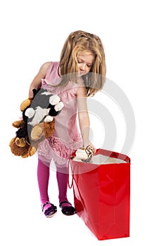 Beautiful little girl taking out toys from a red shopping bag