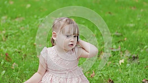 Beautiful little girl talking on a cell phone in the park on the grass.