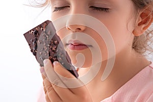 Beautiful little girl taste chocolate like a pro - breaking cacao bar, smelling, eating