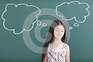 Beautiful little girl thinking before chalkboard