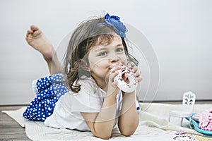 Beautiful little girl with toy dishes, sweets and dolls is playing at the tea party