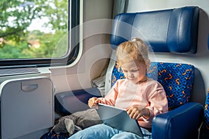 Beautiful Little girl using digital tablet during traveling by railway, Europe