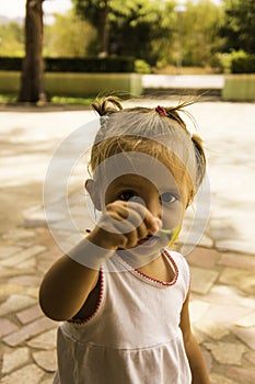 Beautiful little girl walks in the park. she holds a flower and looks at him.