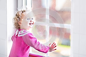 Beautiful little girl watching out of a window