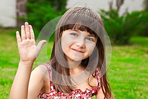 Beautiful little girl waves her hand