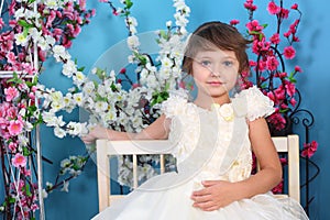 Beautiful little girl in white dress sits on bench