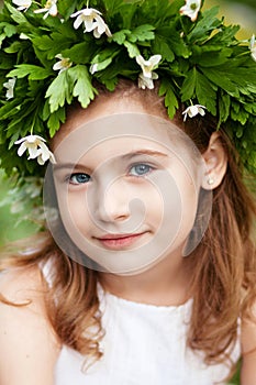 Beautiful  little girl in a white dress  in the spring wood. Portrait of the pretty little girl with a wreath from spring flowers