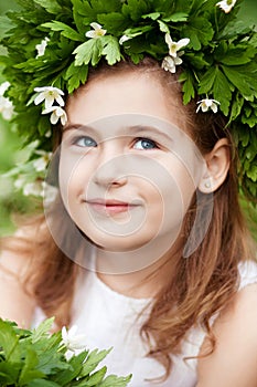 Beautiful  little girl in a white dress  in the spring wood. Portrait of the pretty little girl with a wreath from spring flowers