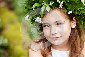 Beautiful  little girl in a white dress  in the spring wood. Portrait of the pretty little girl with a wreath from spring flowers