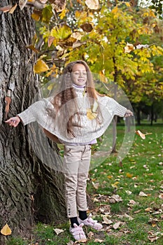 Beautiful little girl in white sweater posing in autumn