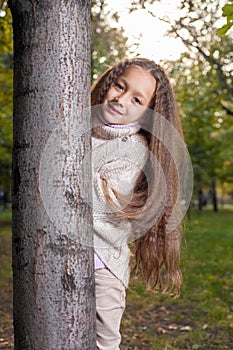 Beautiful little girl in white sweater posing in autumn Park